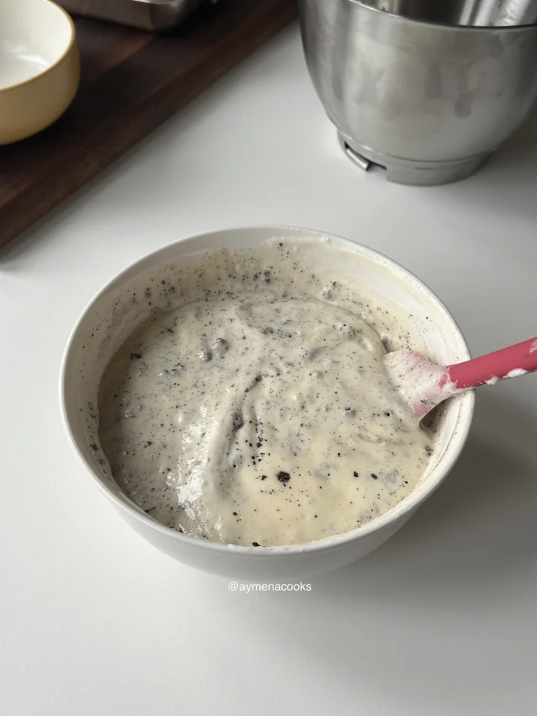 Crushed Oreo crumbs folded through the airy cake batter in a white bowl.