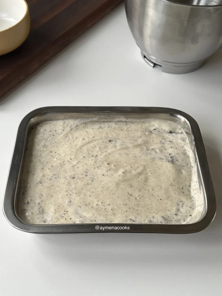 Oreo tres leches cake batter spread evenly in a metal baking pan, ready for the oven.