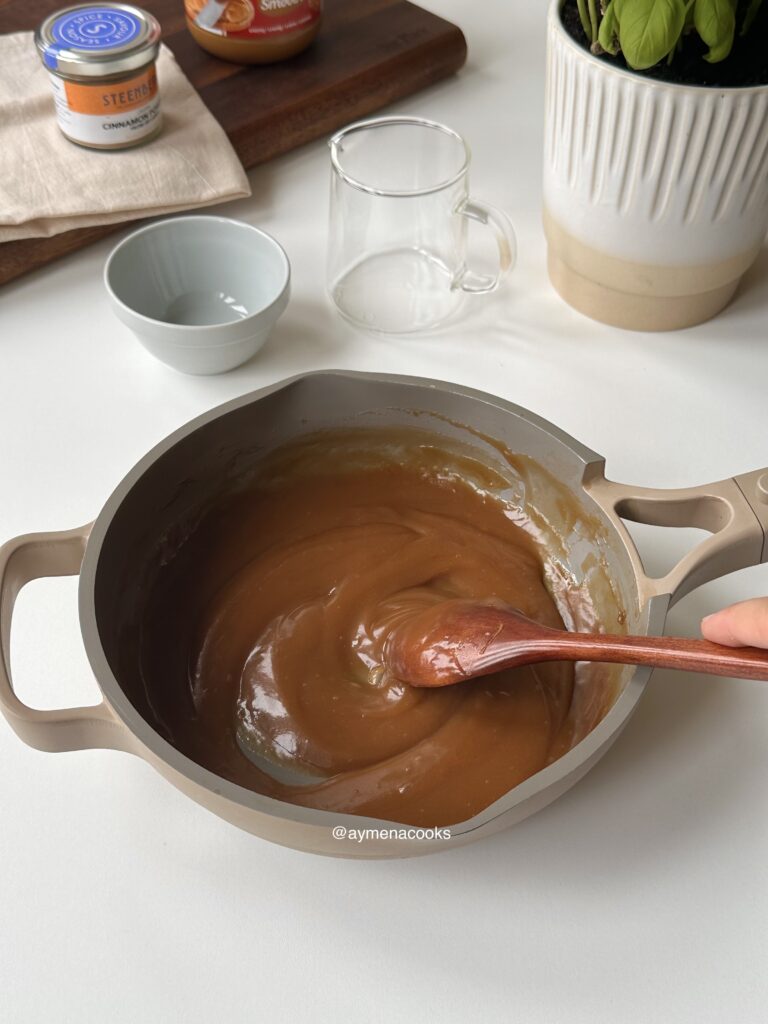 Cookie butter syrup cooking gently in a saucepan while being stirred.