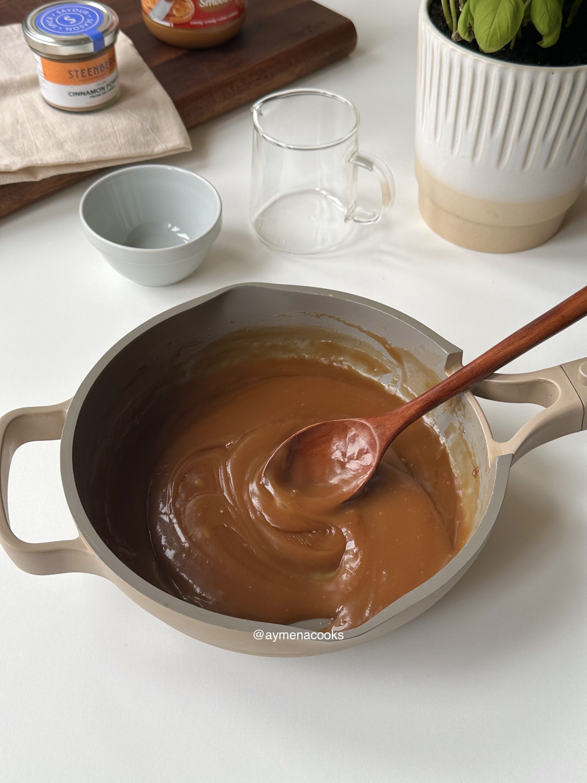 Smooth and glossy homemade cookie butter syrup in a pan with a spoon showing its creamy texture.