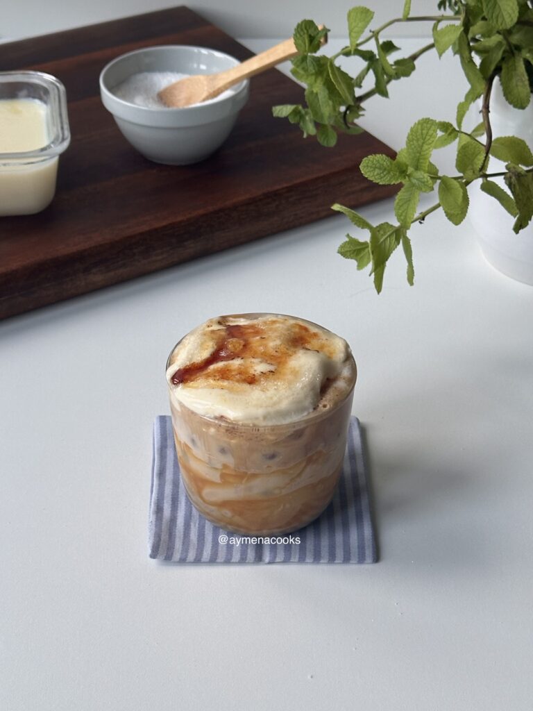 creme brulee latte in a glass resting on a striped fabric coaster
