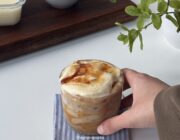 Creme brulee latte in a glass with a torched sugar top, held on a striped napkin