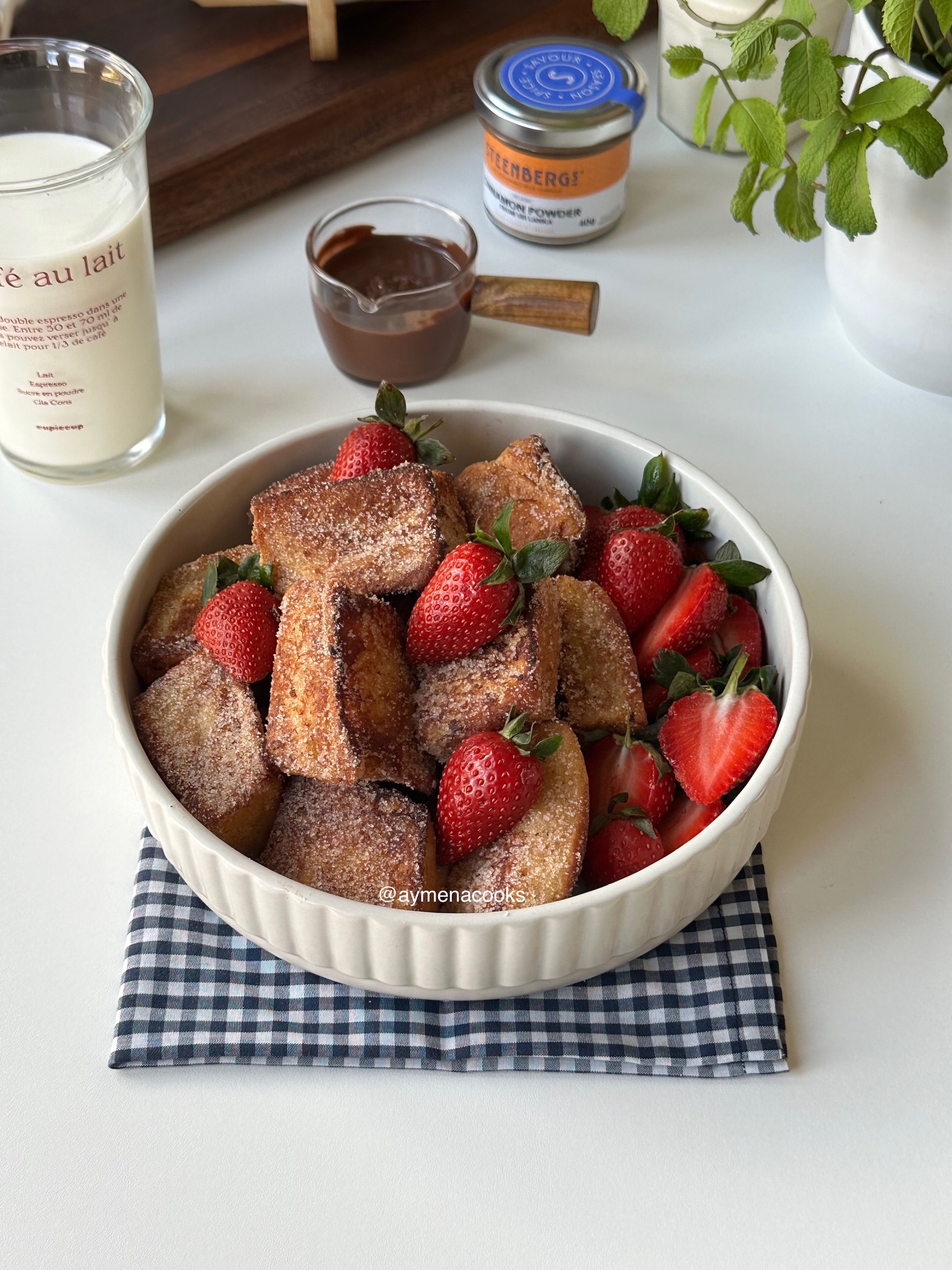 Golden cinnamon-sugar French toast bites piled in a bowl with fresh strawberries.