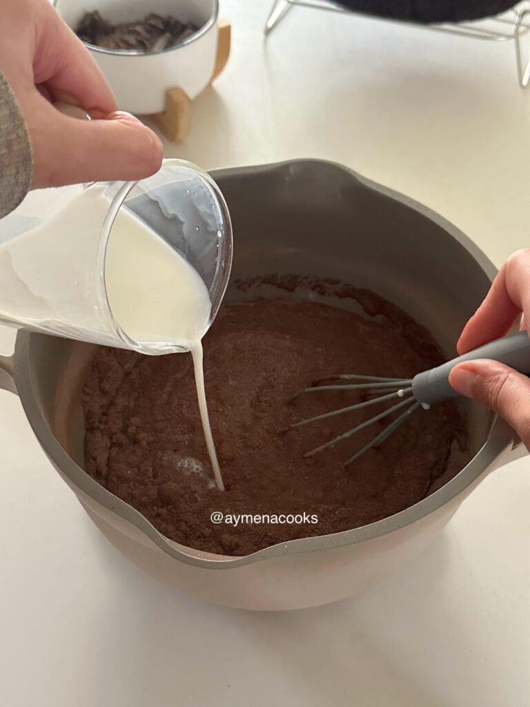Milk being poured into the dry ingredients for the chocolate fudge frosting.
