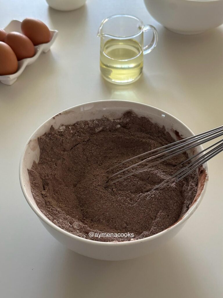 Flour, cocoa powder, sugars and raising agents whisked together for Matilda chocolate cake.