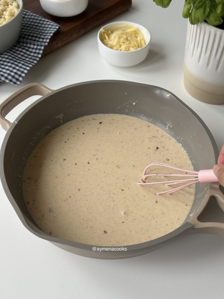 Seasonings being whisked into the milk and cream sauce until smooth.