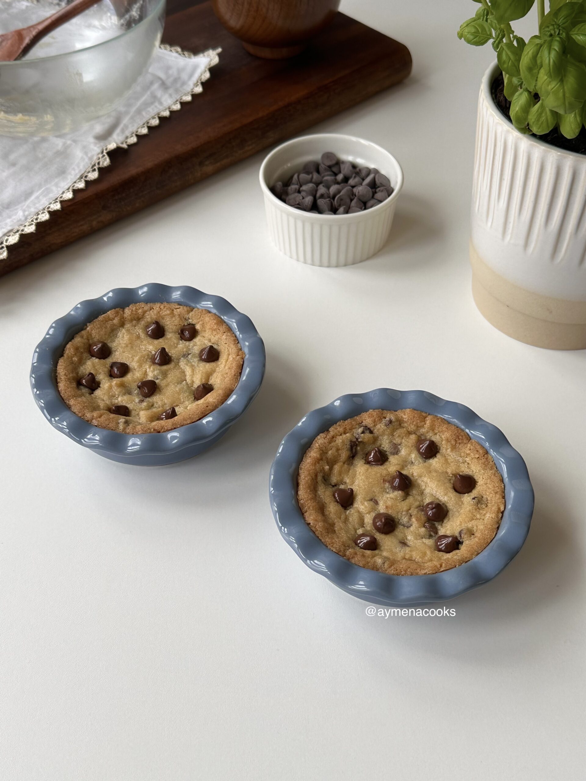 Two warm mini chocolate chip cookie pies in individual blue pie dishes.
