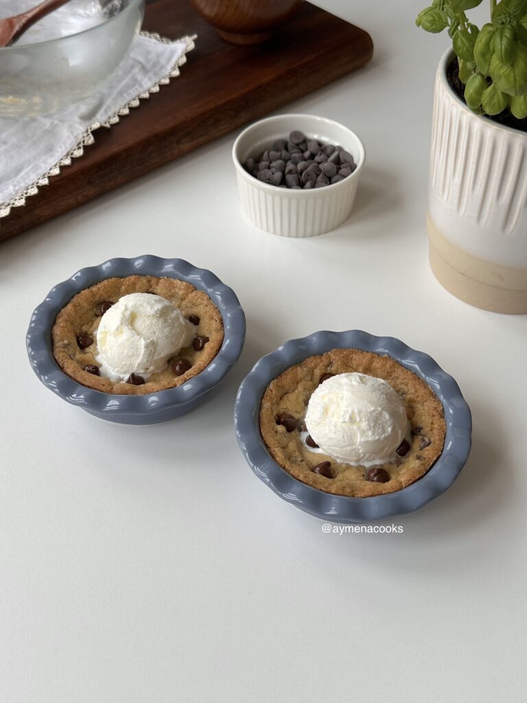 Two baked mini cookie pies served warm in small blue pie dishes with vanilla ice cream.