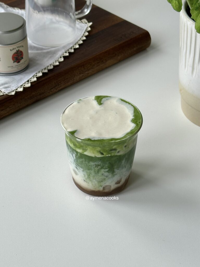 Banana cold foam poured over an iced banana matcha latte.
