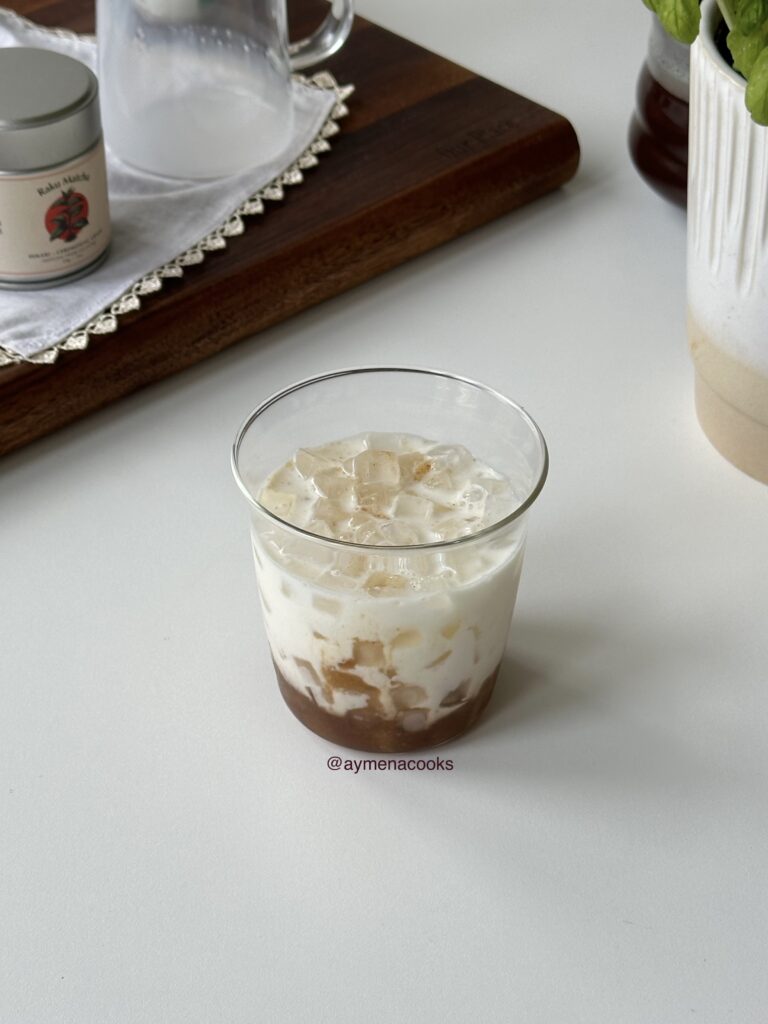 Cold milk poured over banana bread syrup and ice for banana matcha.