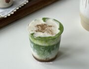 Layered iced banana matcha topped with creamy banana cold foam and a light dusting of cinnamon.