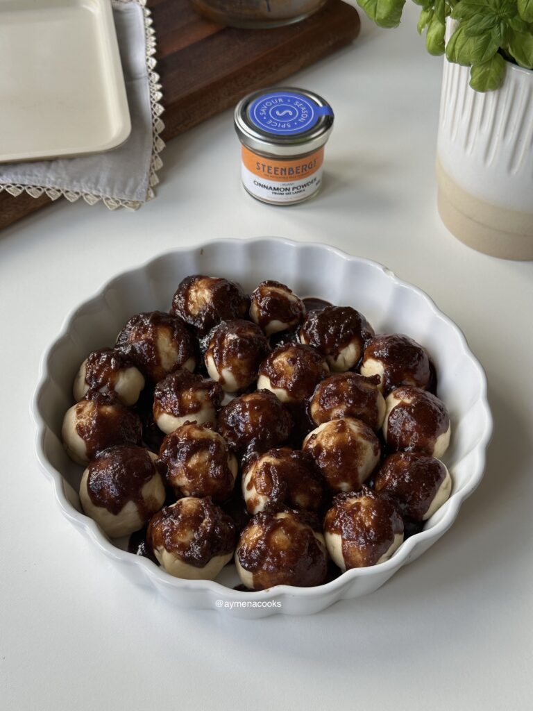 Brown sugar cinnamon topping poured over cinnamon roll bites.