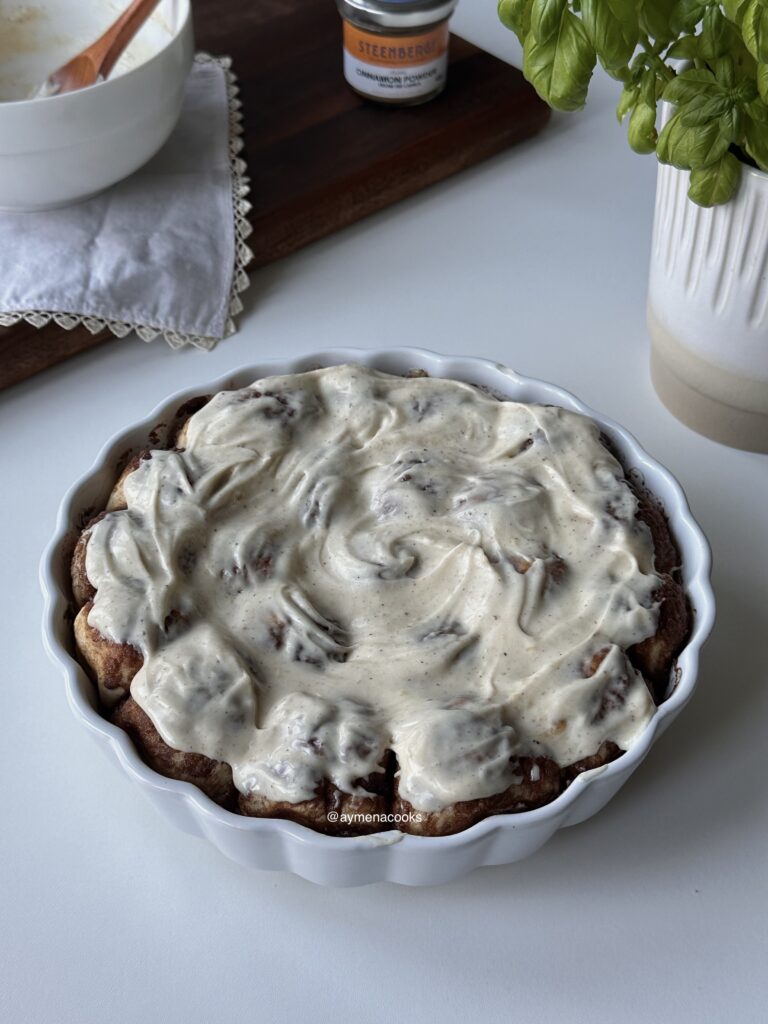 Pull-apart cinnamon roll bites covered with cream cheese frosting in a baking dish.