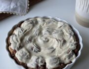 Warm cinnamon roll bites in a baking dish topped with brown butter cream cheese frosting.
