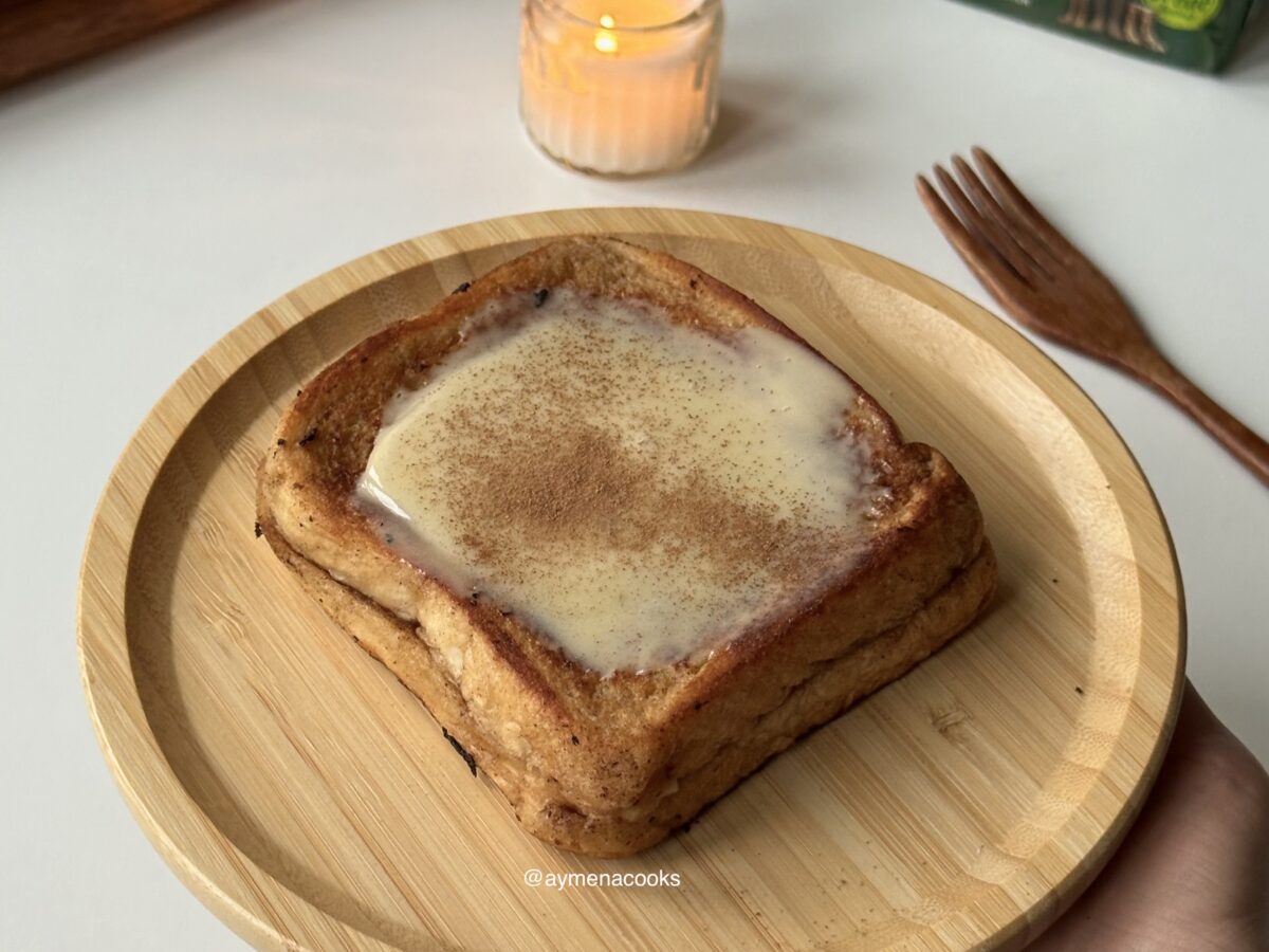 Cinnamon roll French toast topped with cream cheese frosting and a light dusting of cinnamon.