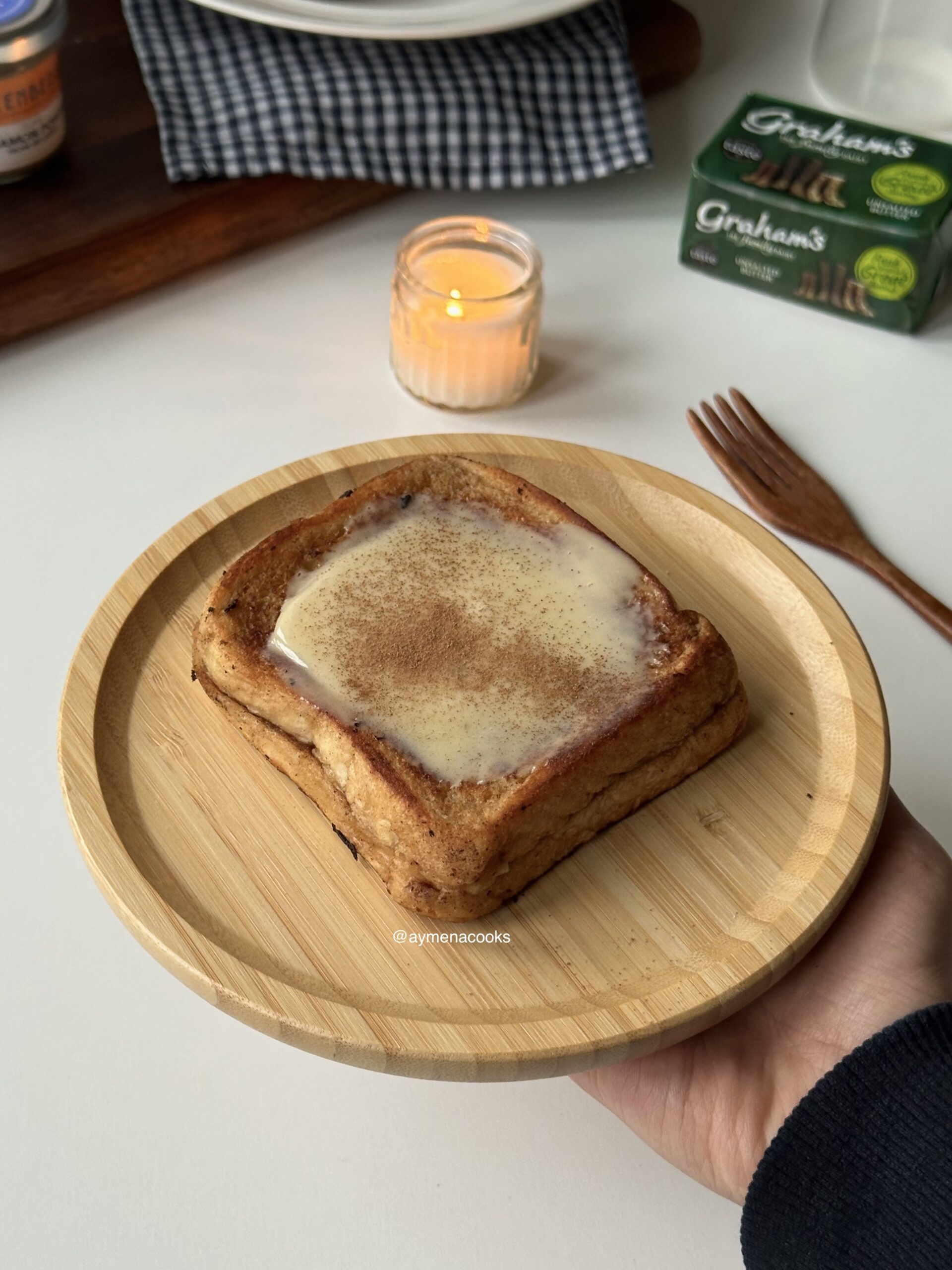 Cinnamon roll French toast topped with cream cheese frosting and a light dusting of cinnamon.