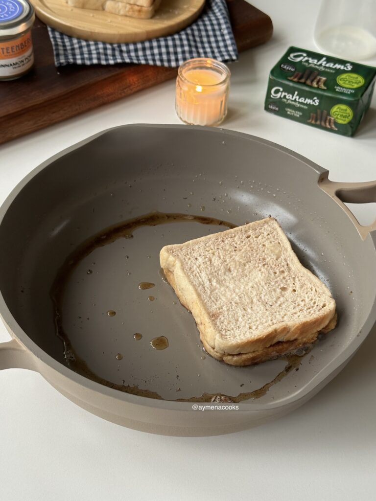 Cinnamon roll French toast cooking in butter in a nonstick pan.