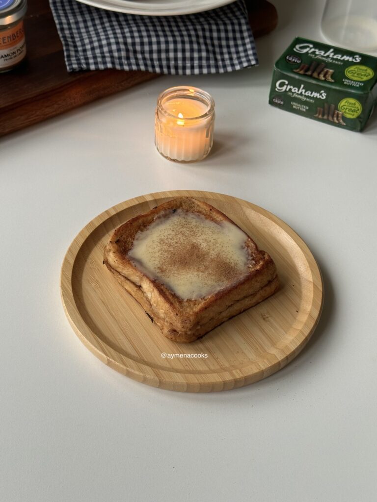 Cinnamon roll French toast topped with cream cheese frosting and cinnamon.
