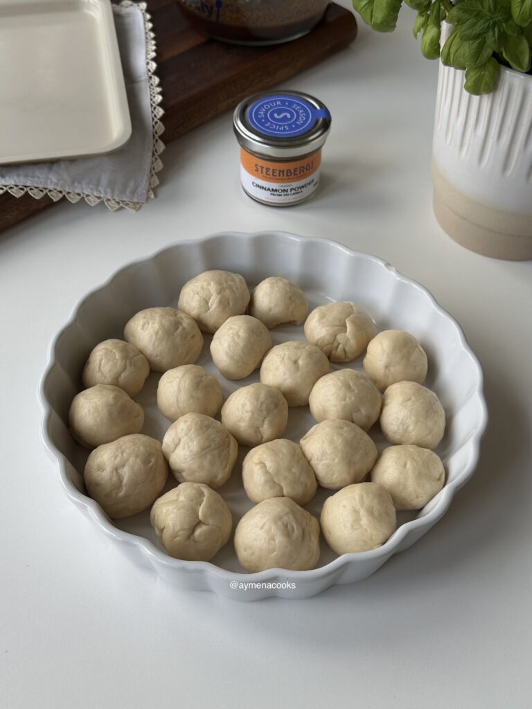 Cinnamon roll bites arranged in a greased round baking dish.