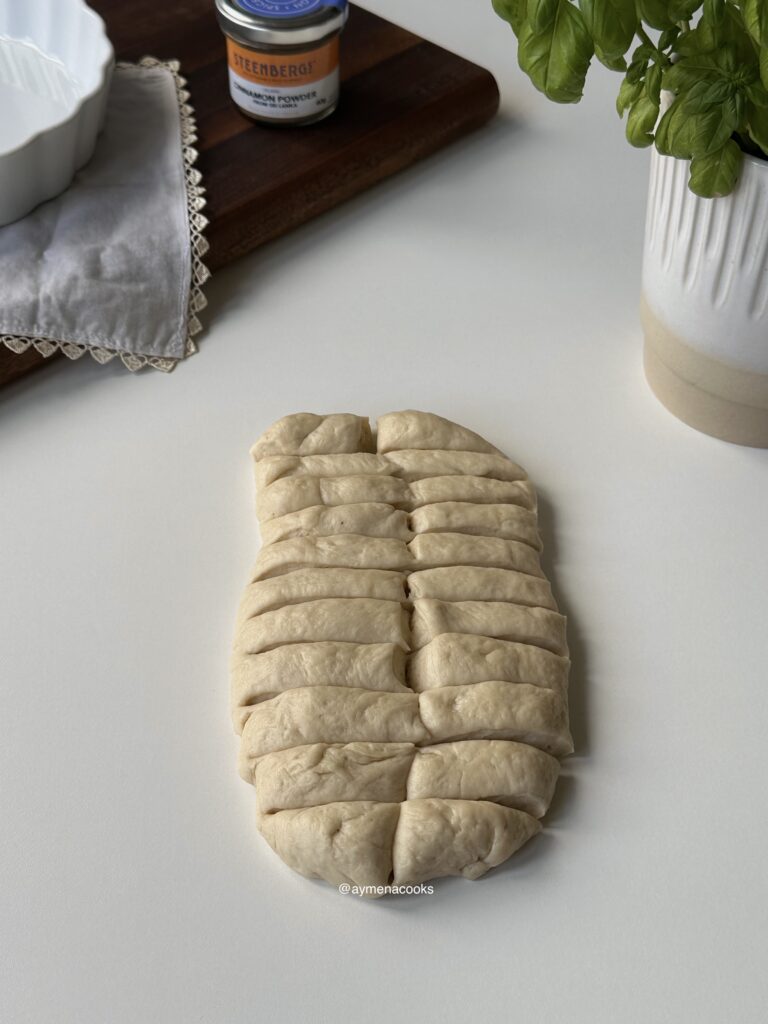 Cinnamon roll dough shaped into a thick rectangle, sliced lengthways and then horizontally to create even bite-size pieces.