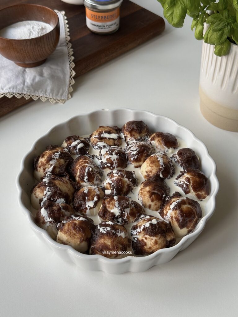 Unbaked cinnamon roll bites covered with brown sugar cinnamon topping and heavy cream.